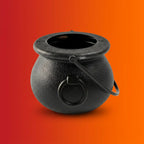 Black cast iron Halloween witch cauldron with a metal handle on orange-red gradient background.