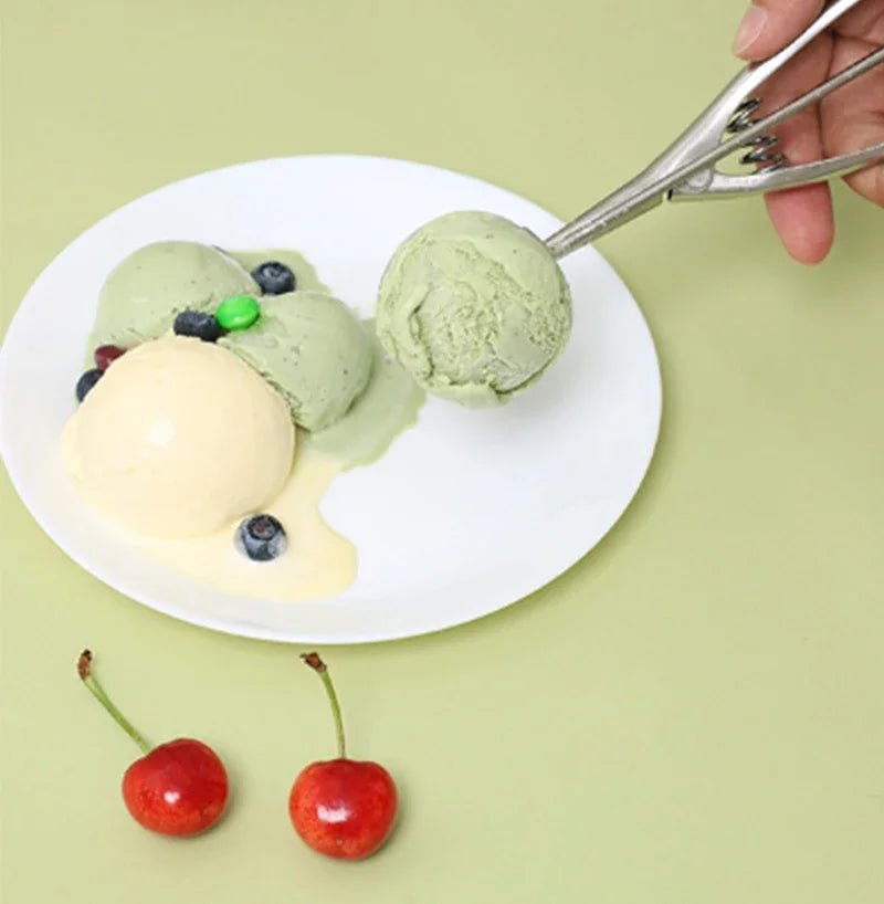 Stainless steel spring scoop held above a plate of ice cream balls