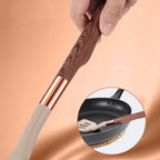 Close-up of beige silicone spatula head and rose-gold handle held by hand