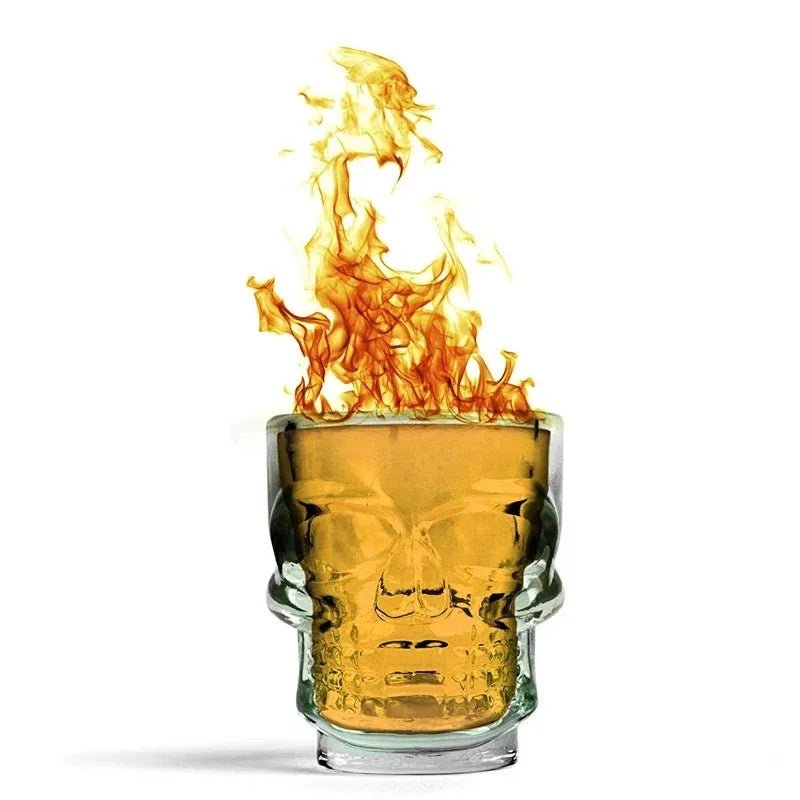 Skull head shot glass filled with amber liquid, flames rising above the rim
