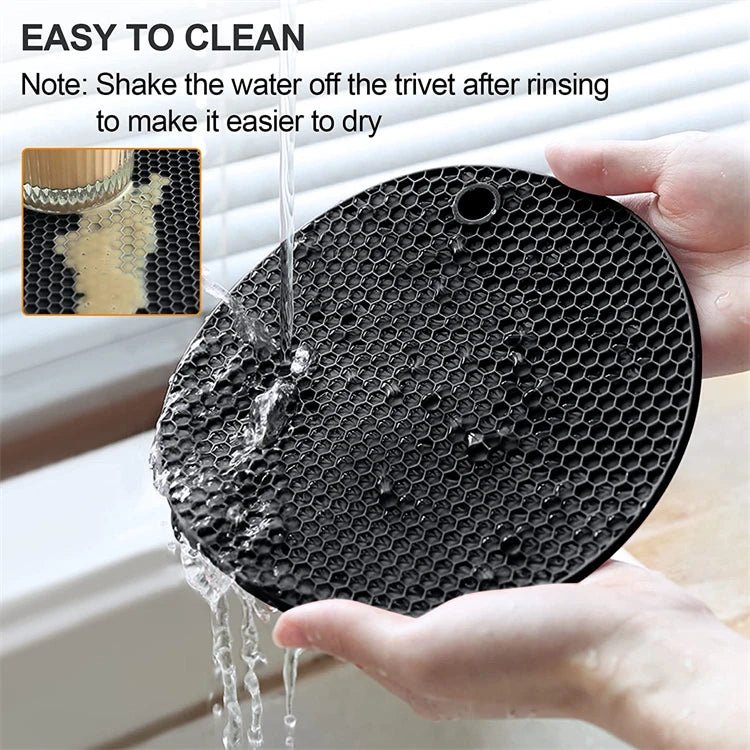 Black silicone trivet mat with honeycomb pattern, held under faucet water