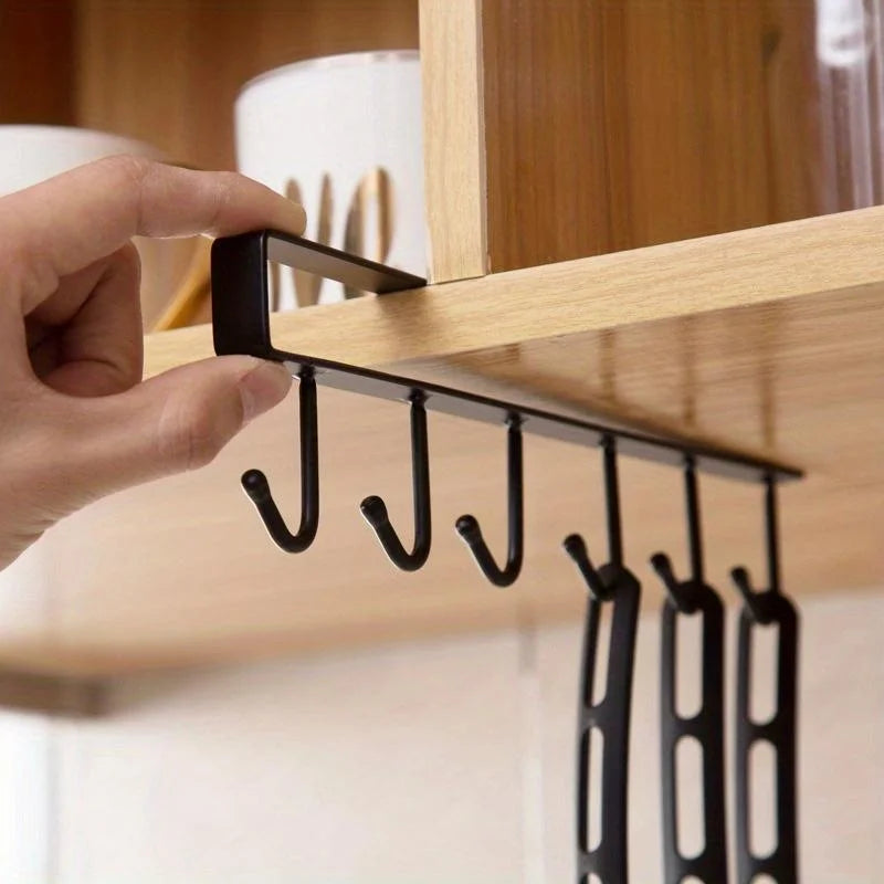 Under-cabinet 6-hook mug hanger, hand sliding the matte black rack onto a shelf