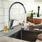 Gray silicone drain mat under faucet with water channels and cup on countertop