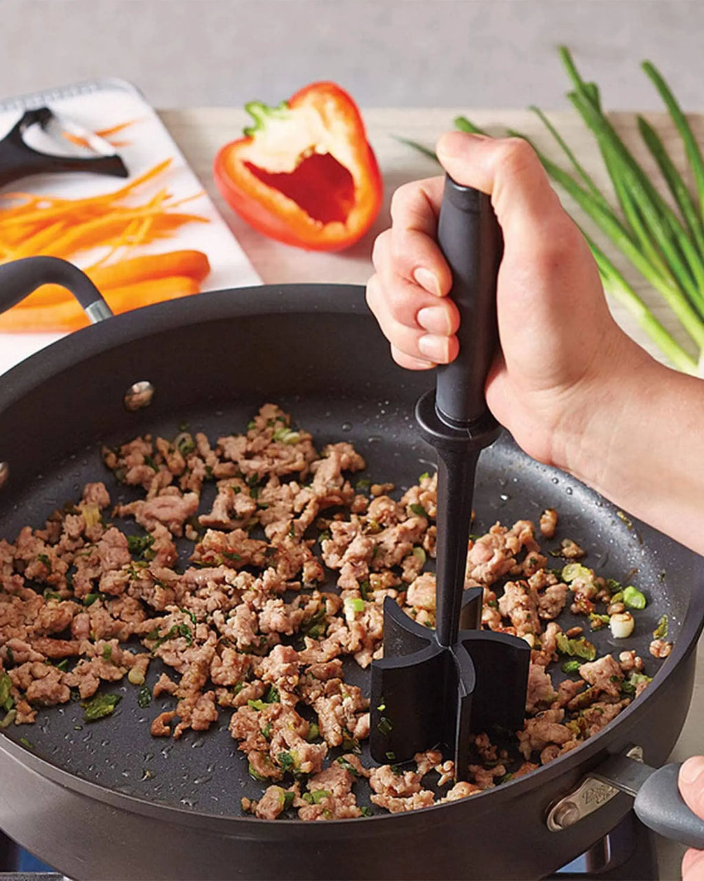 Black 5-blade meat chopper mashing meat in a skillet