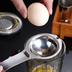 Stainless steel egg separator with long handle, yolk cup over bowl