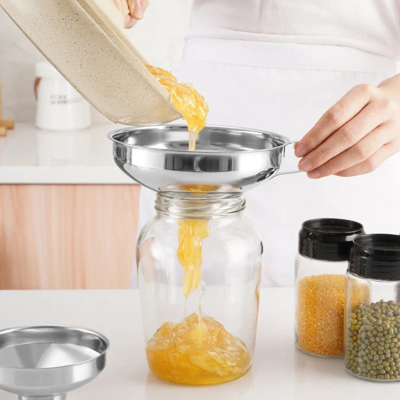 Stainless steel canning funnel pouring into a glass mason jar