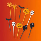 Halloween food picks with spider, bat, jack-o-lantern pumpkin, ghost, and skull shapes in orange, black, and white on orange-red gradient background.