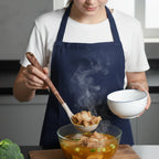 Cook holding a beige silicone spatula with rose-gold handle over a pot of food