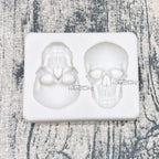Skull silicone cake mold tray with two skull cavities; white skull cakes set inside