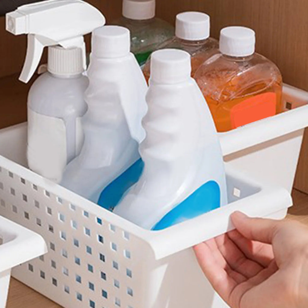 White under-sink organizer basket holding cleaning spray bottles